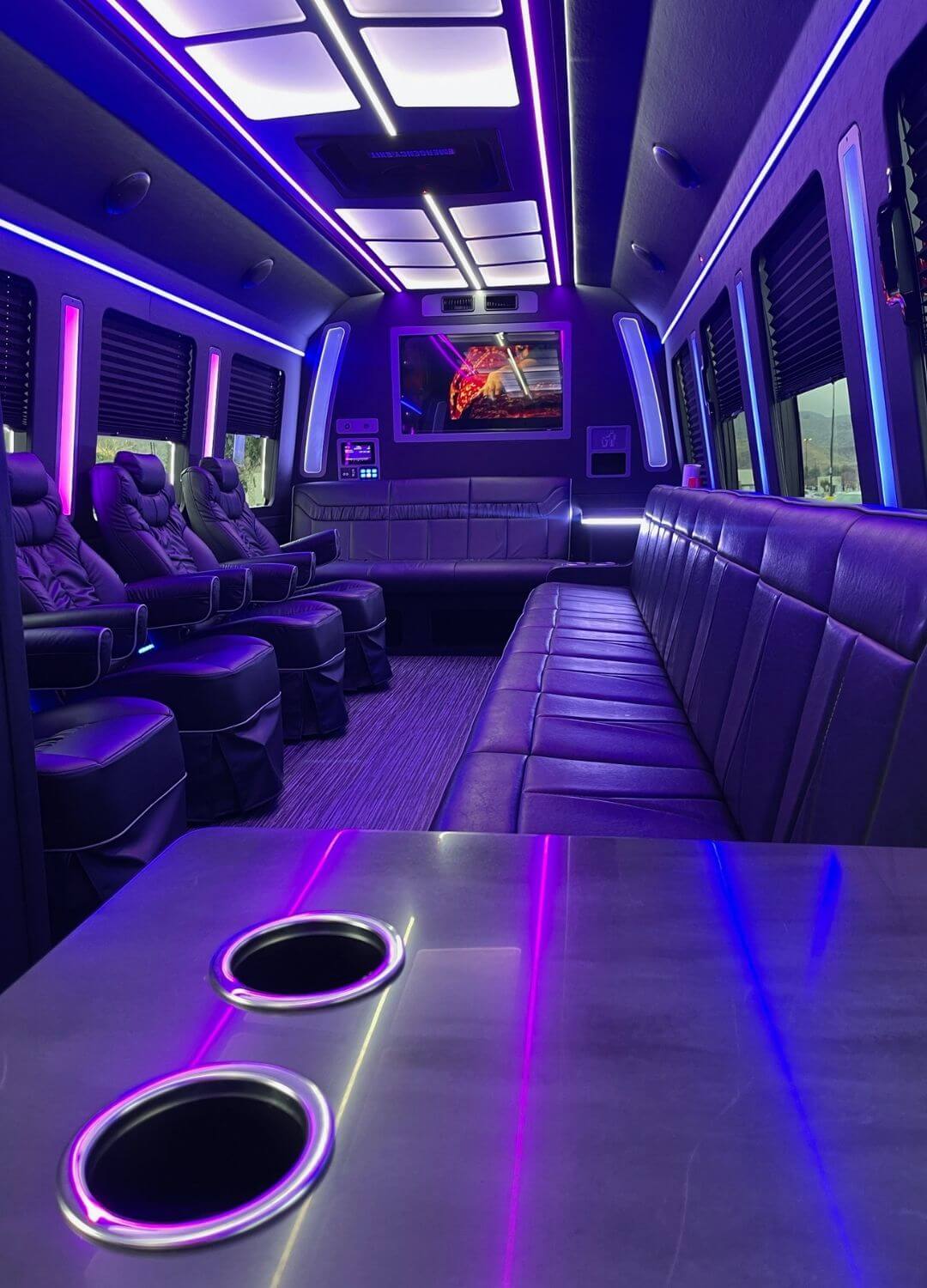 luxury bus interior with leqather couches, captain seats, adn entertainment system.
